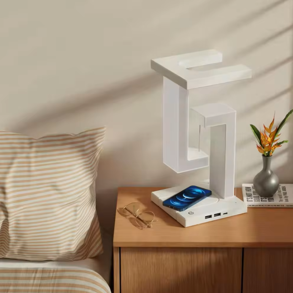 Modern white desk lamp on a wooden nightstand with a vase and newspaper in the background.