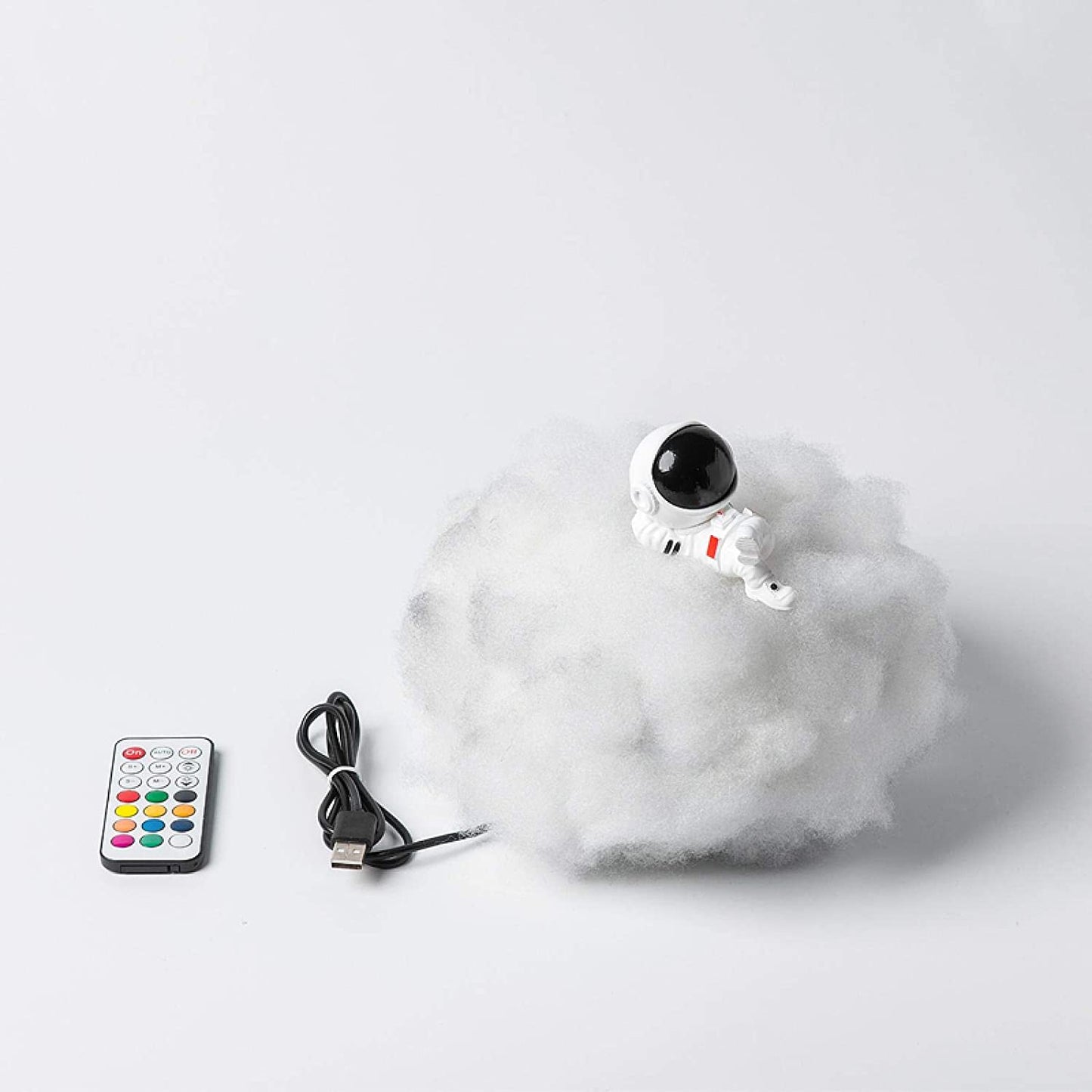 Toy robot on a cloud with a remote control and USB cable on a white background