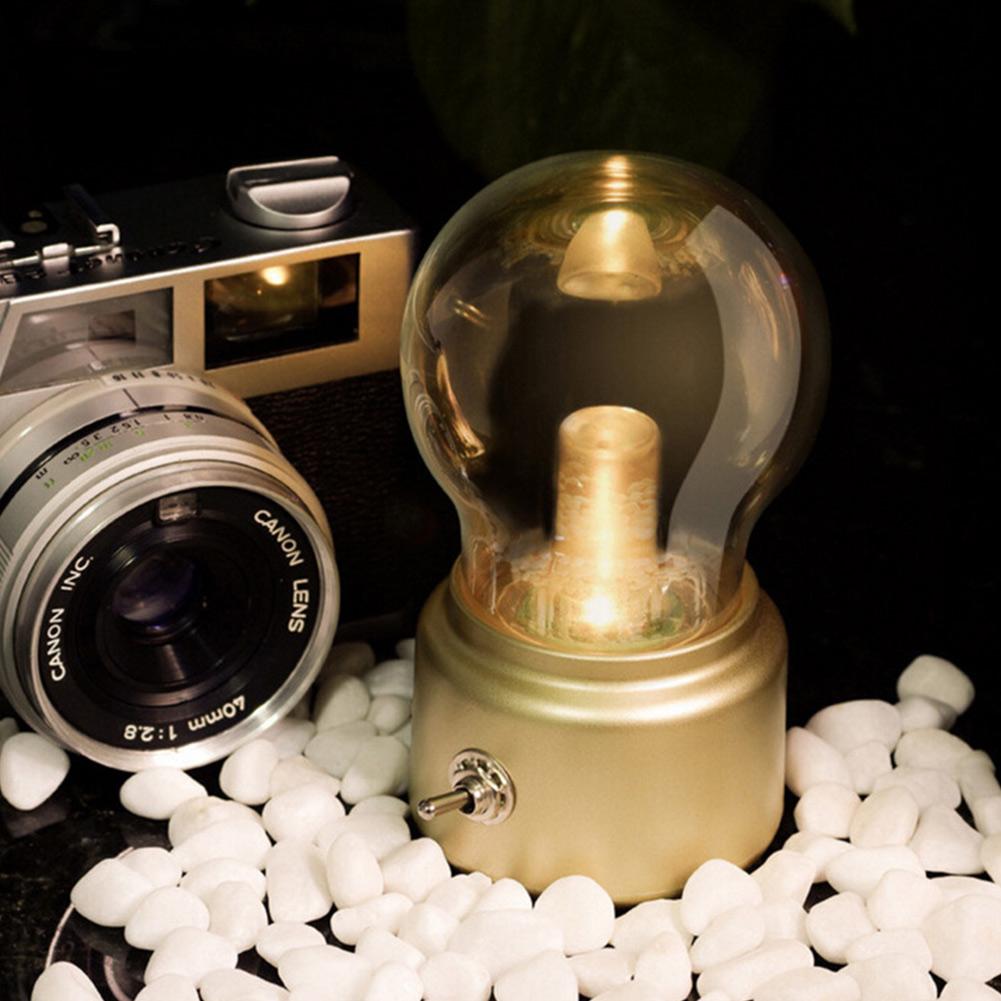 Vintage camera next to a light bulb in a glass dome on a dark background