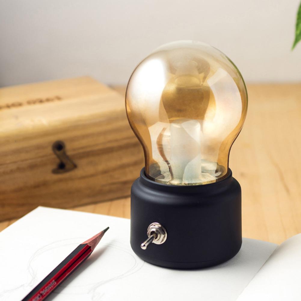 Small lamp with a light bulb design on a desk next to a pencil