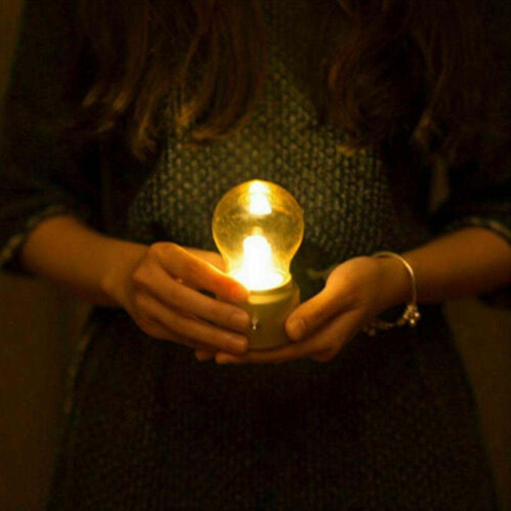 Person holding a light bulb in a dark setting