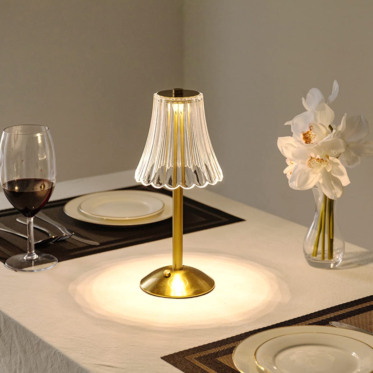 Gold table lamp on a dining table with wine glass and plates