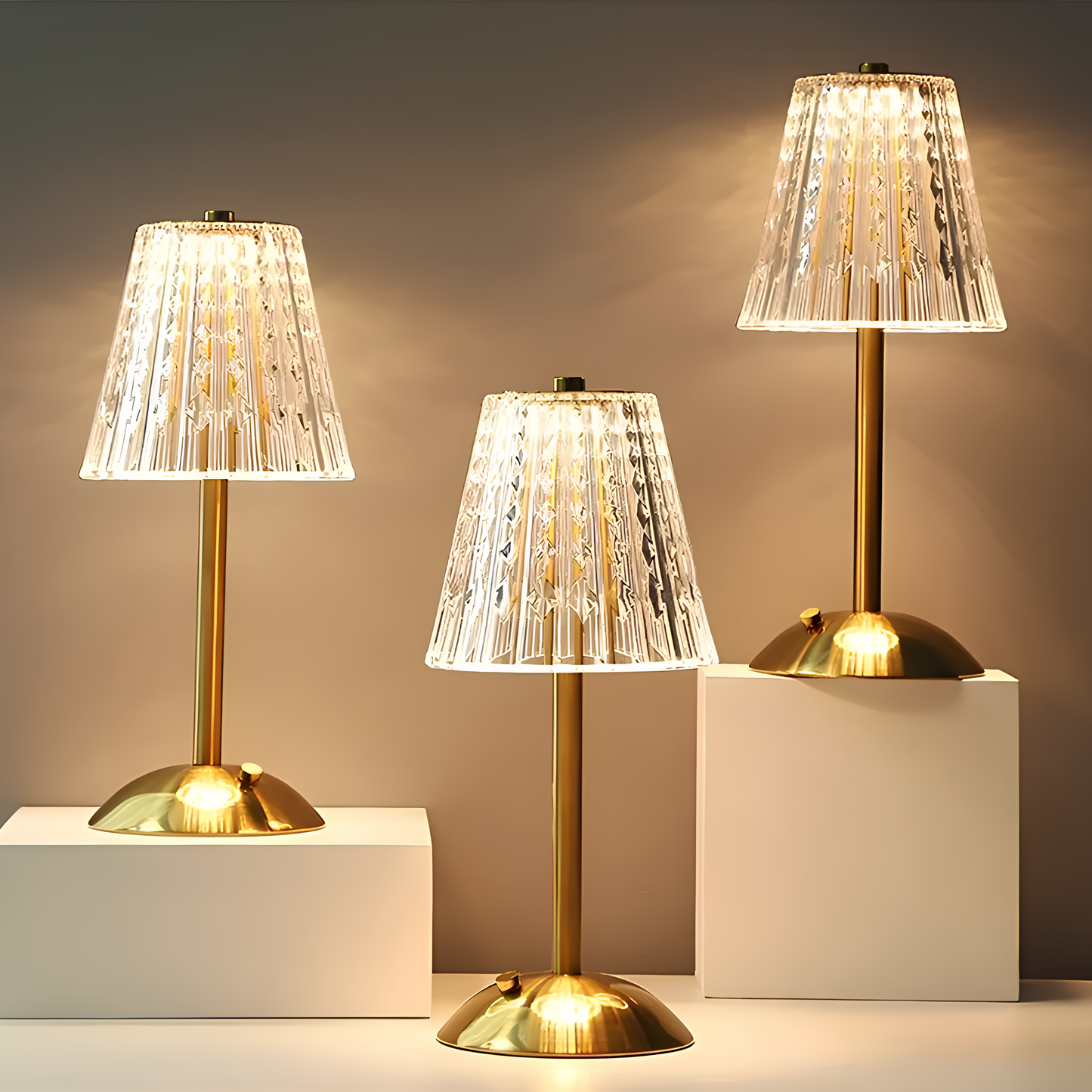 Three table lamps with gold bases and clear, ribbed lampshades on a neutral background.