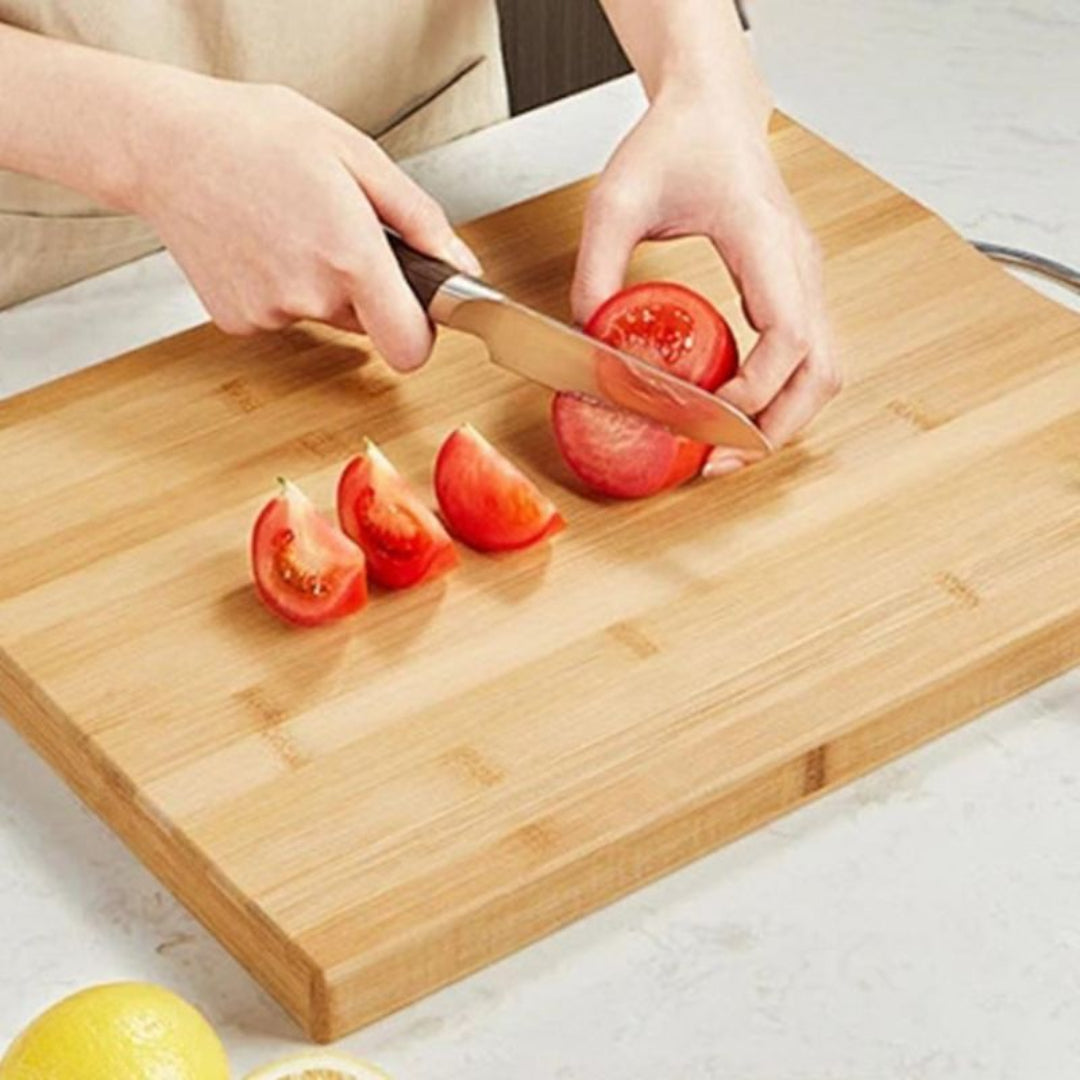 Person slicing tomatoes on a wooden cutting board with a knife.