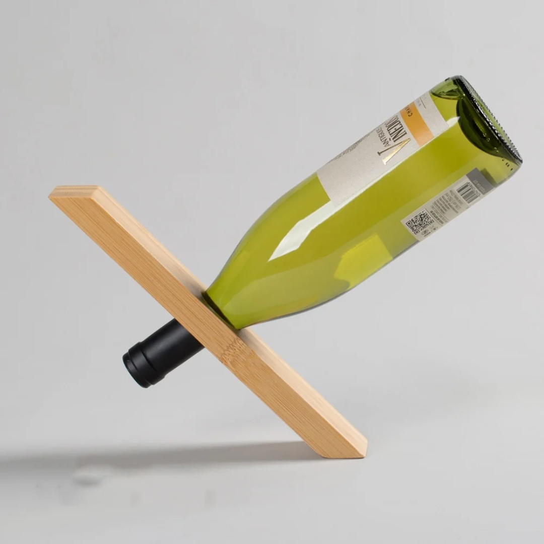 Wine bottle balanced on a wooden stand against a gray background