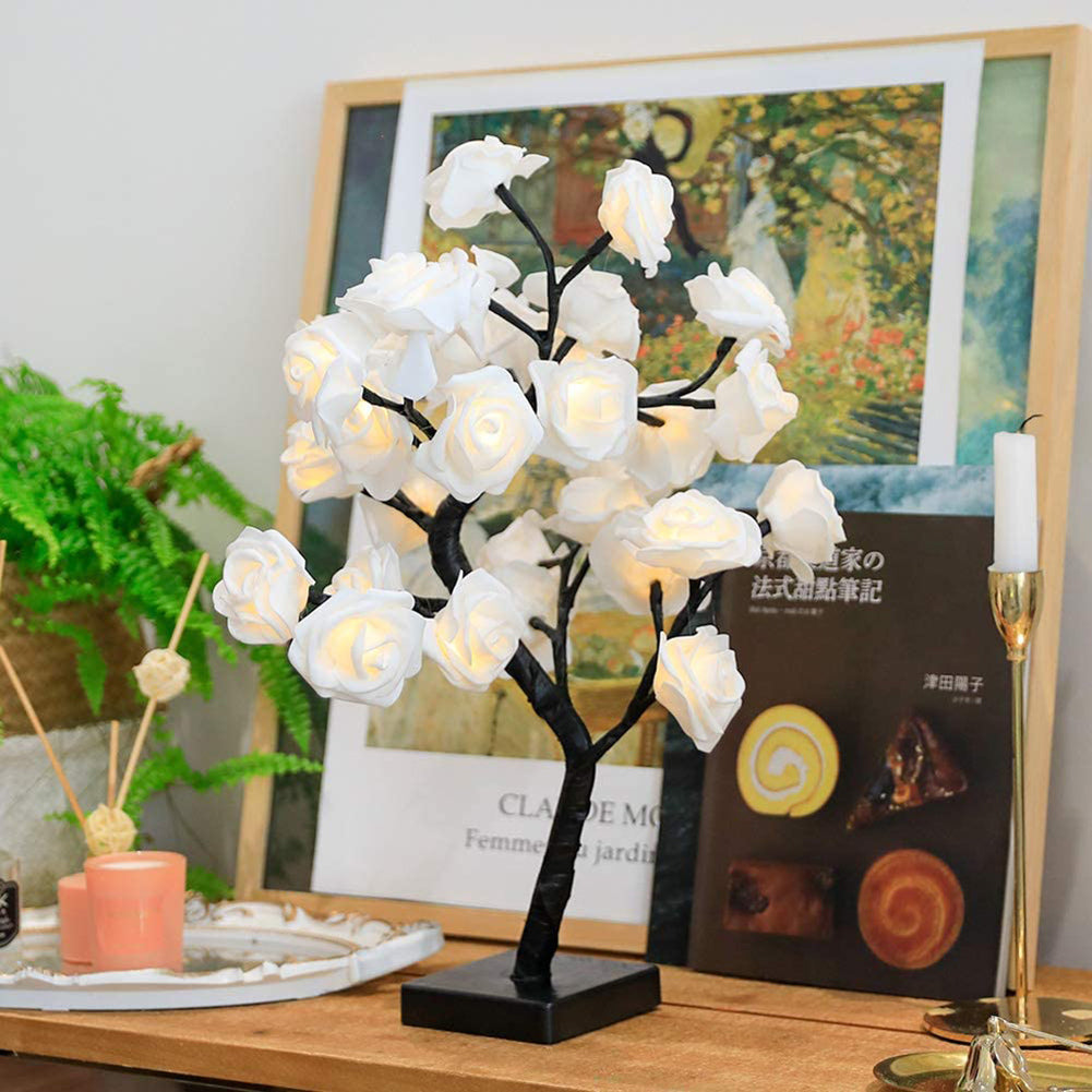 Decorative white flower lamp on a table with a book and candle in the background