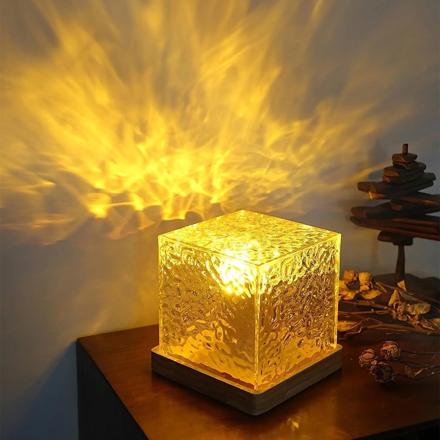 Glass cube lamp emitting a warm glow on a wooden surface with a blurred background