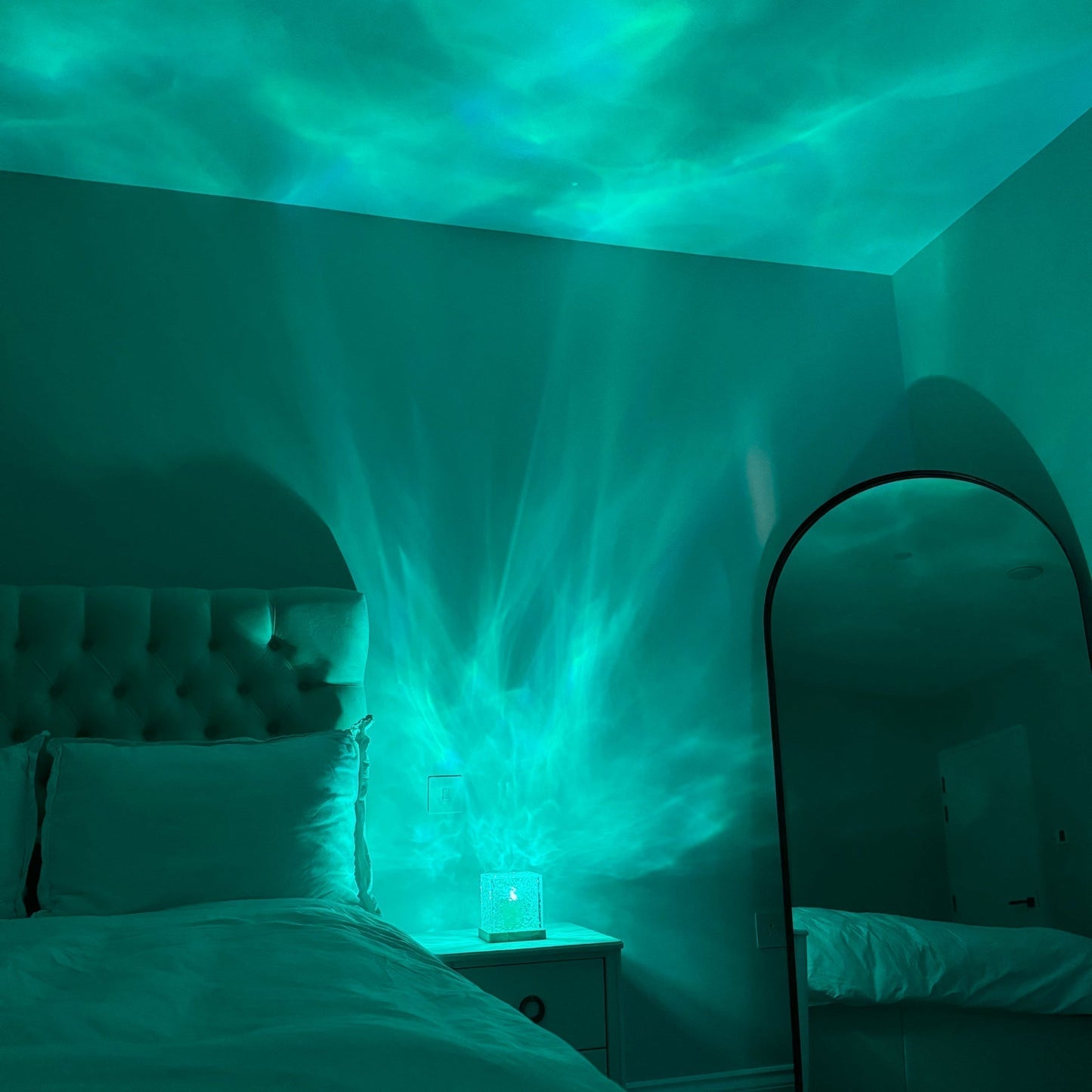 Bedroom with teal lighting effect on the ceiling and walls, creating a relaxing atmosphere.