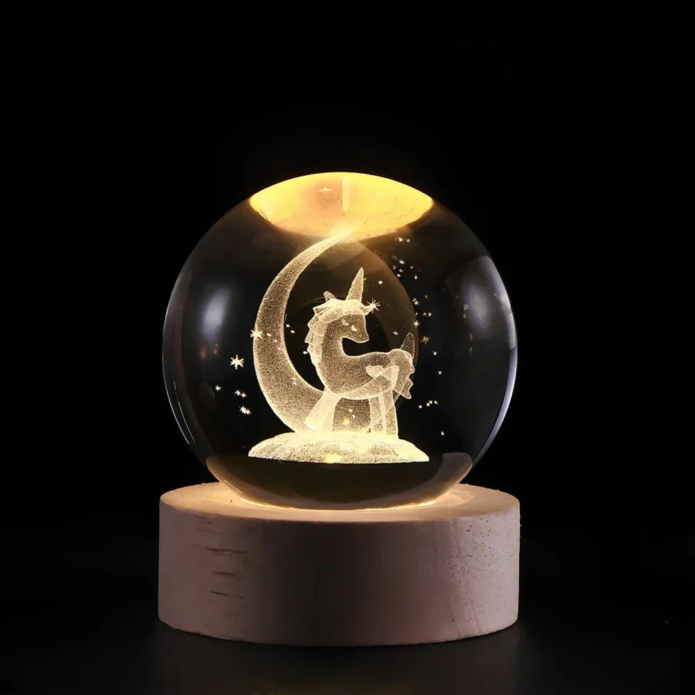 Glass orb with unicorn and moon design on a wooden base against a black background