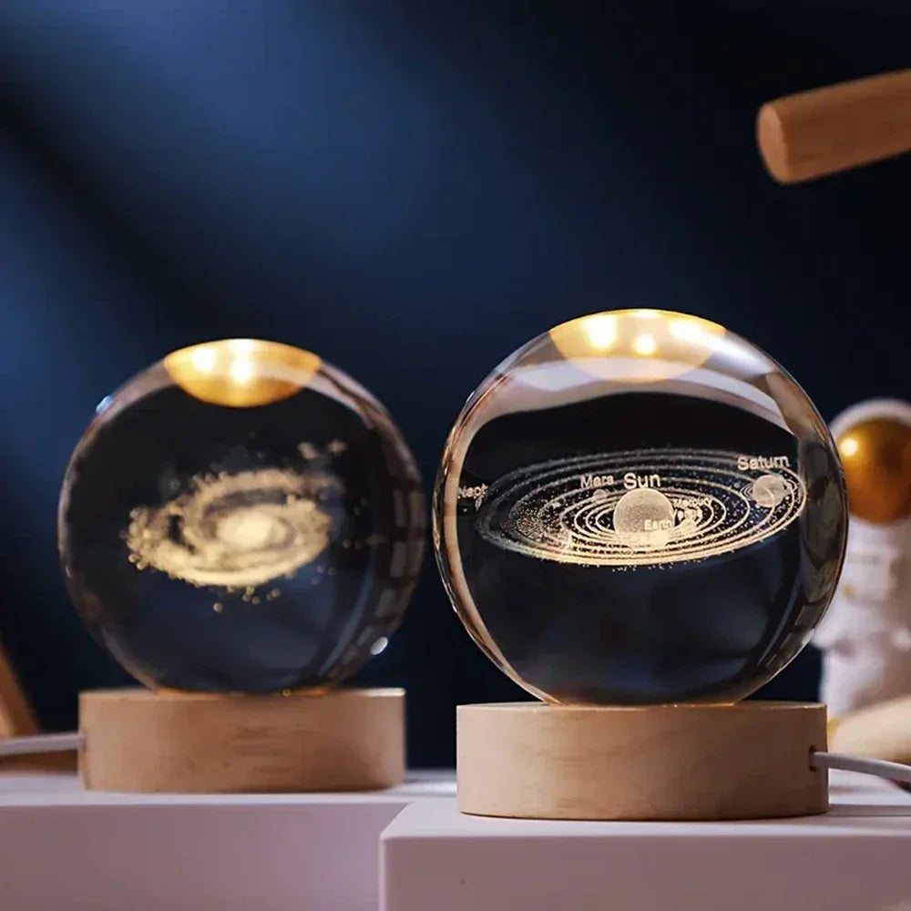 Two glass spheres with solar system models on wooden bases against a dark background