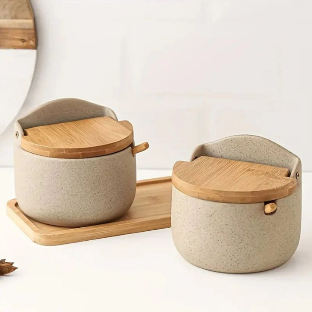 Two ceramic containers with wooden lids on a white surface