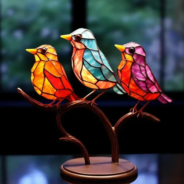 Colorful stained glass birds on a branch against a blurred natural background