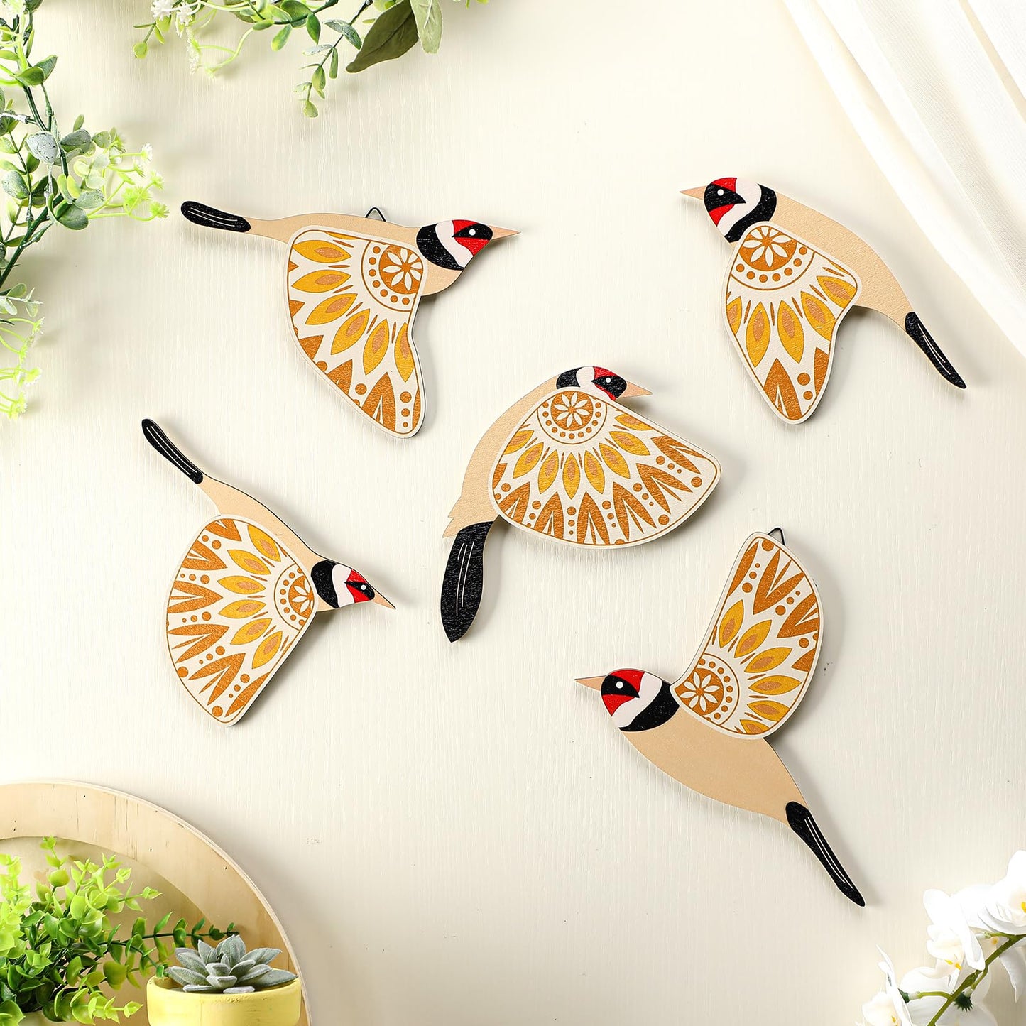 Decorative wall hooks shaped like birds with mandala designs on a light background.