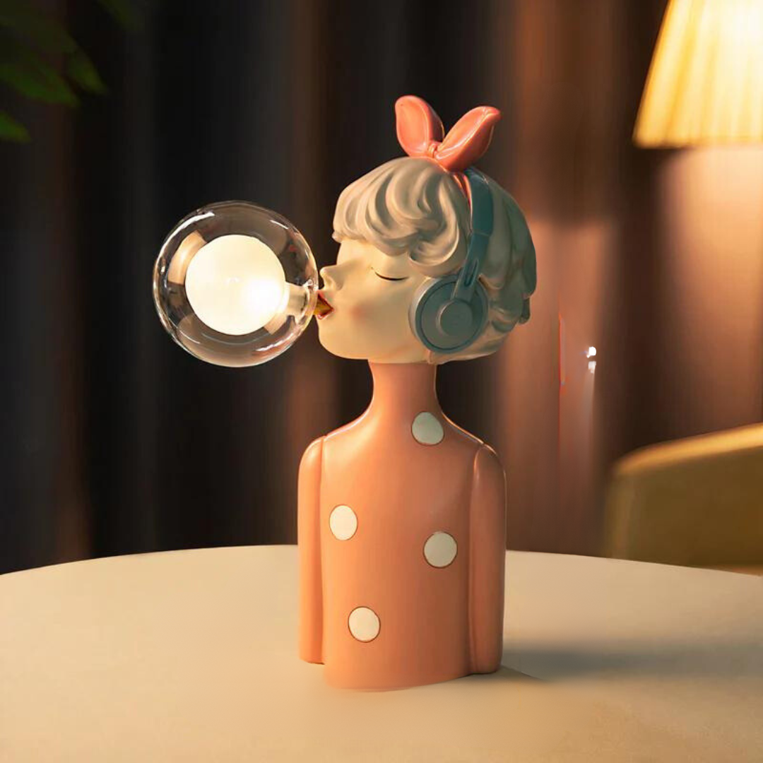 Decorative lamp shaped like a girl blowing a bubble with a light bulb inside, on a blurred background.
