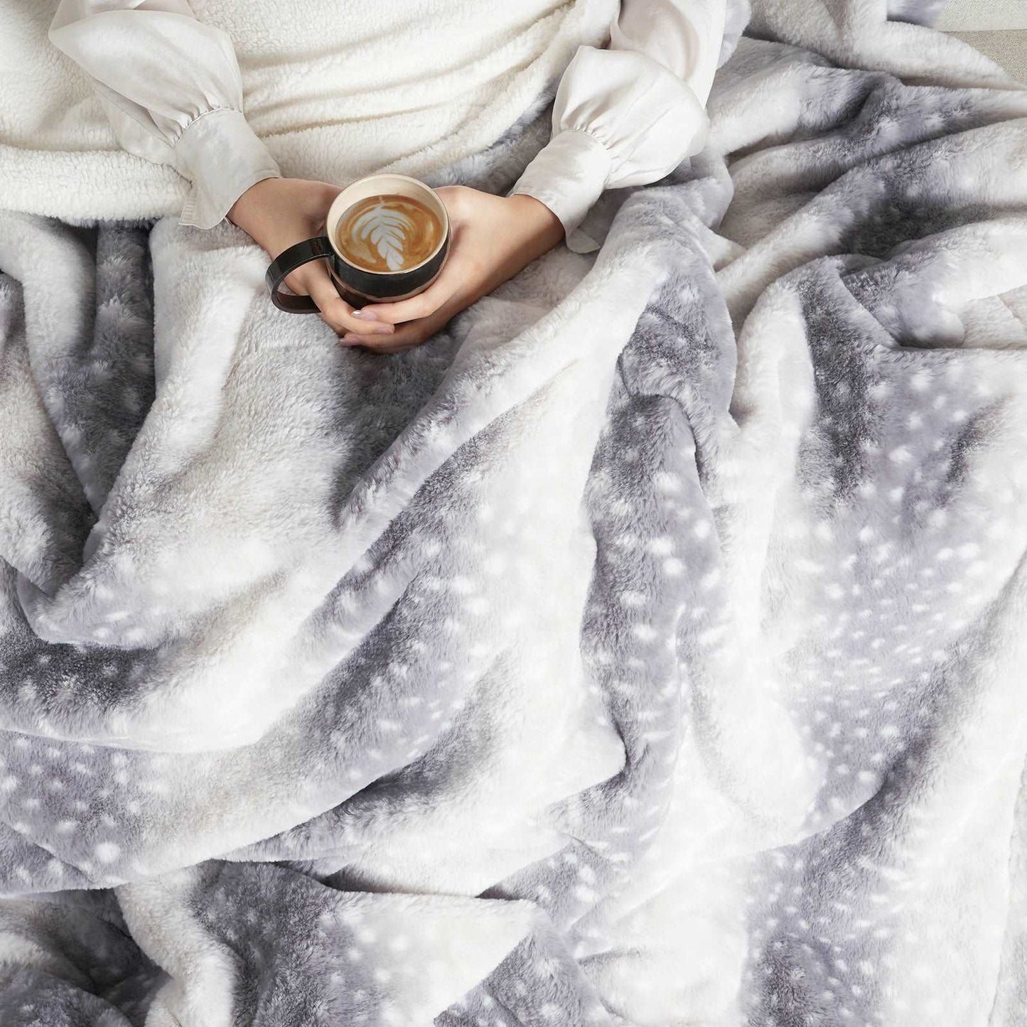Person holding a coffee cup wrapped in a soft, patterned blanket