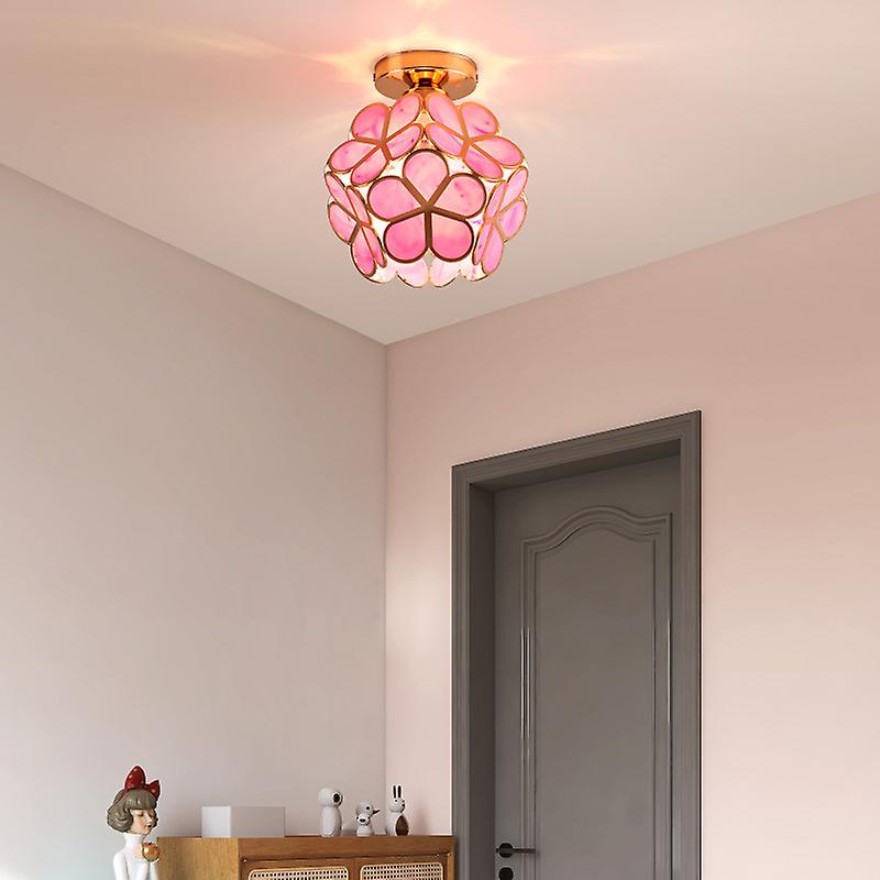 Pink floral ceiling light fixture in a room with a gray door and small table.