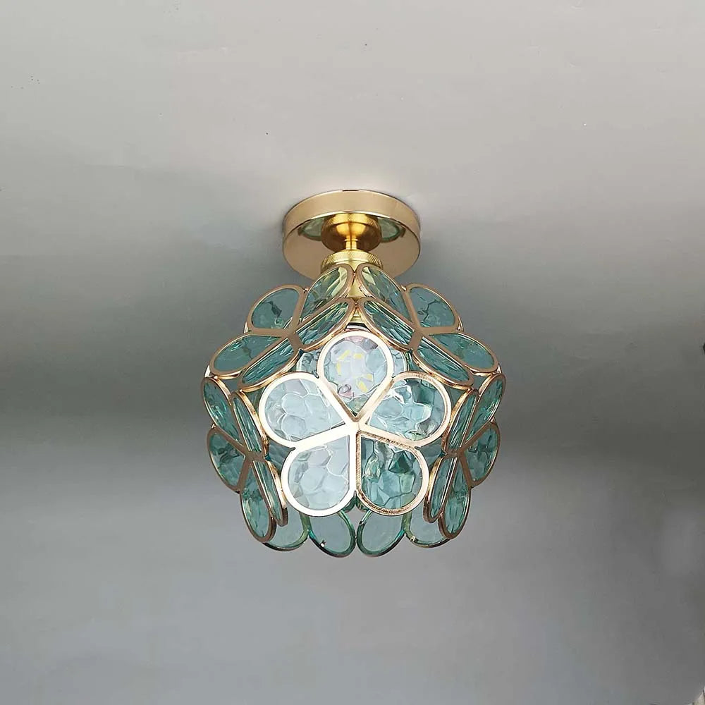 Ceiling light fixture with green glass and gold accents on a neutral background