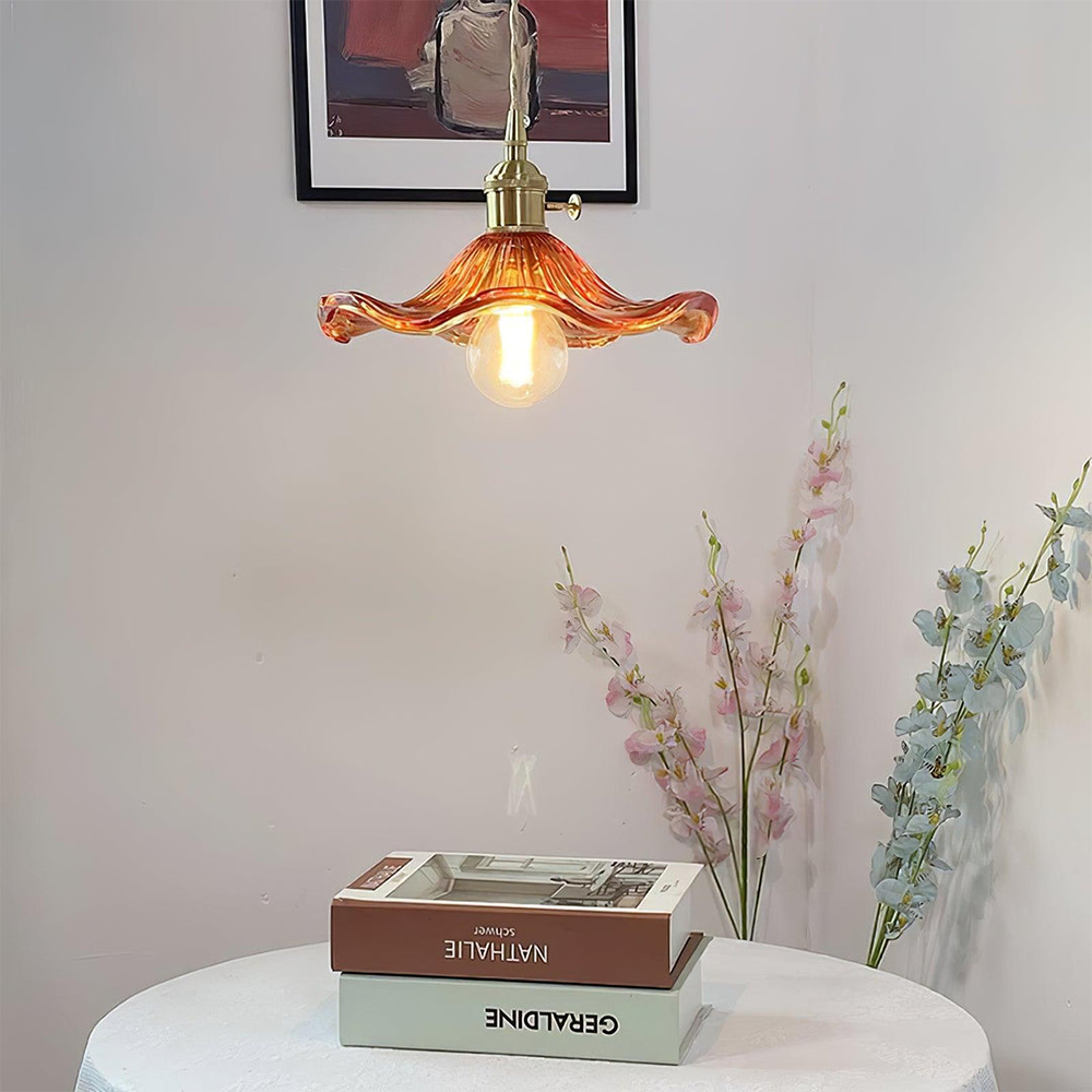 Decorative pendant light with a warm glow above books on a table, with flowers in the background.