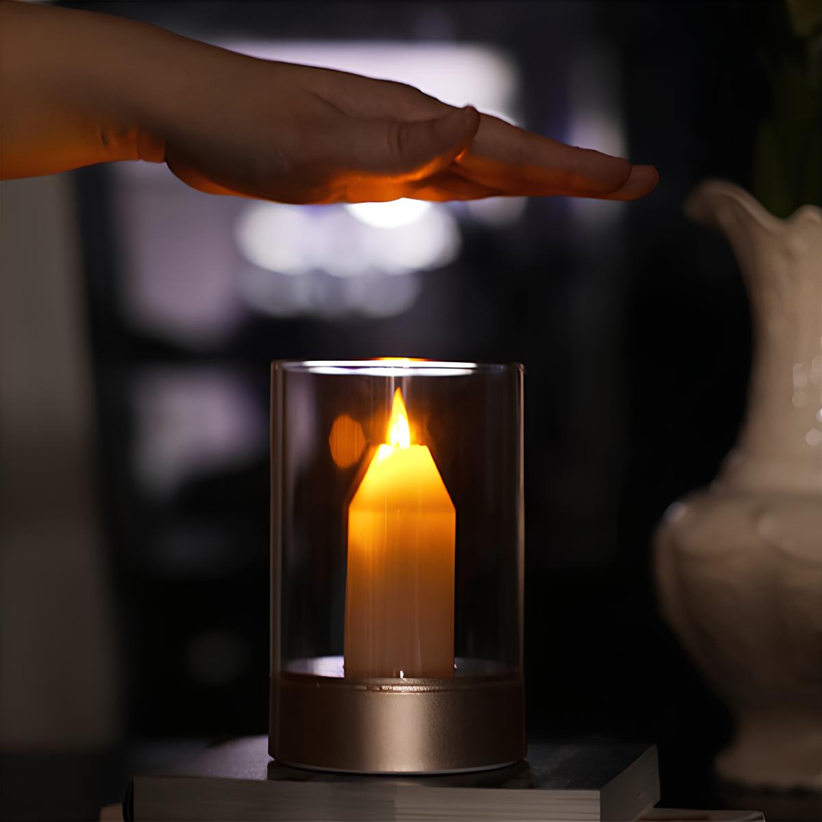Hand holding a glass cover over a lit candle in a dark setting