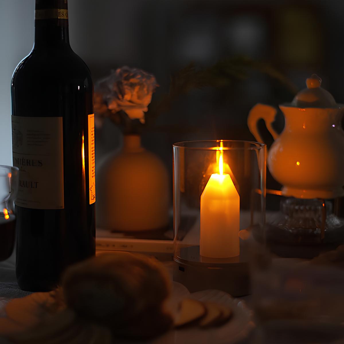 Wine bottle, lit candle, and teapot on a table with a warm glow.