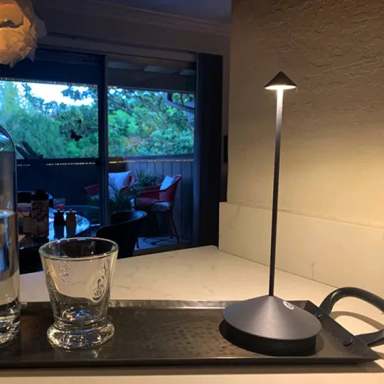 Lamp on a table with a glass and water bottle in front of a window