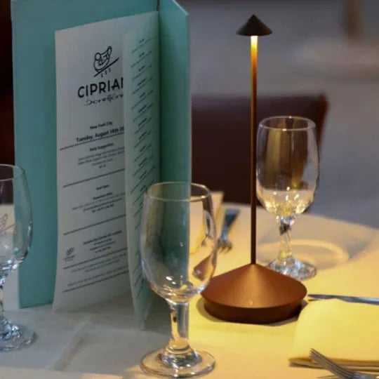 Dinner table setting with wine glasses, a menu, and a candle.