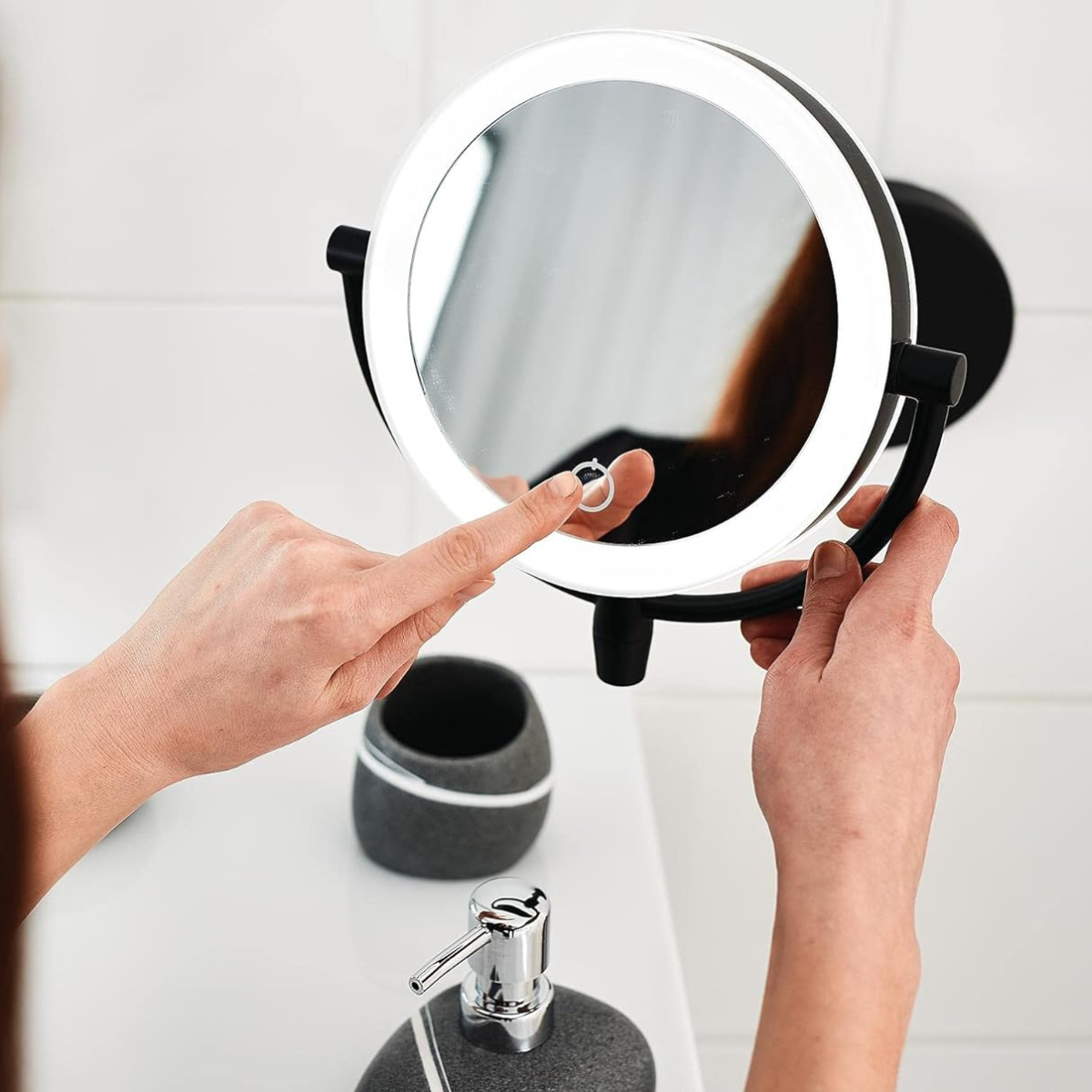 Person using a handheld mirror to check their reflection in a bathroom setting.