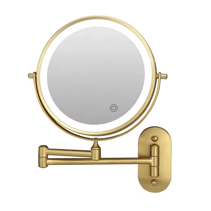 Gold wall-mounted makeup mirror with a light on a white background