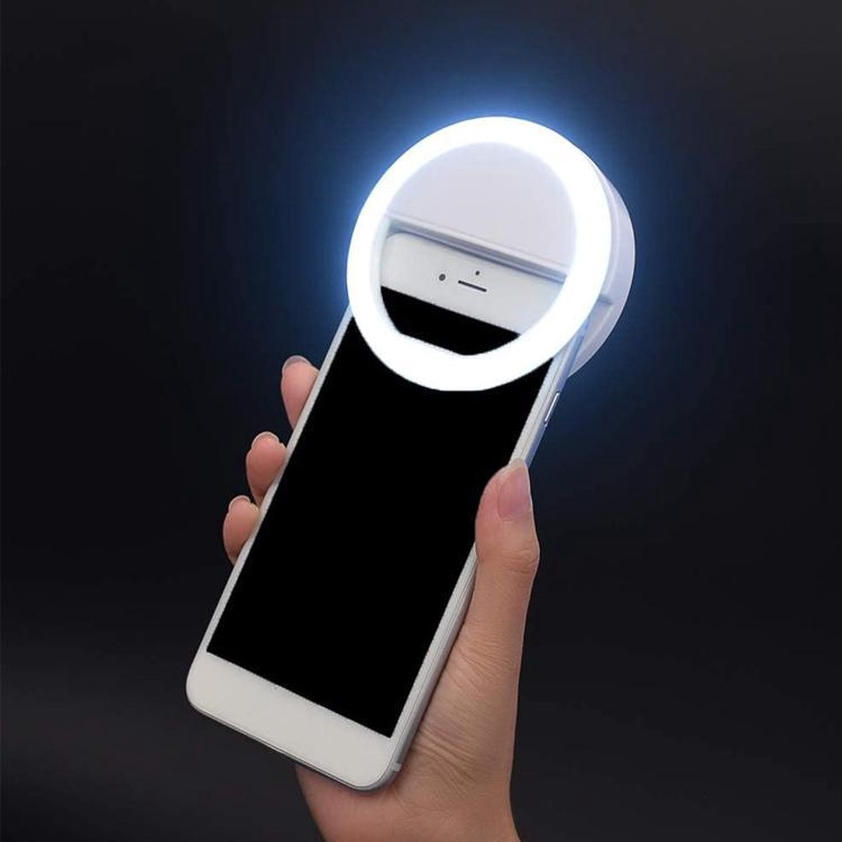 Hand holding a smartphone with a ring light attachment against a dark background