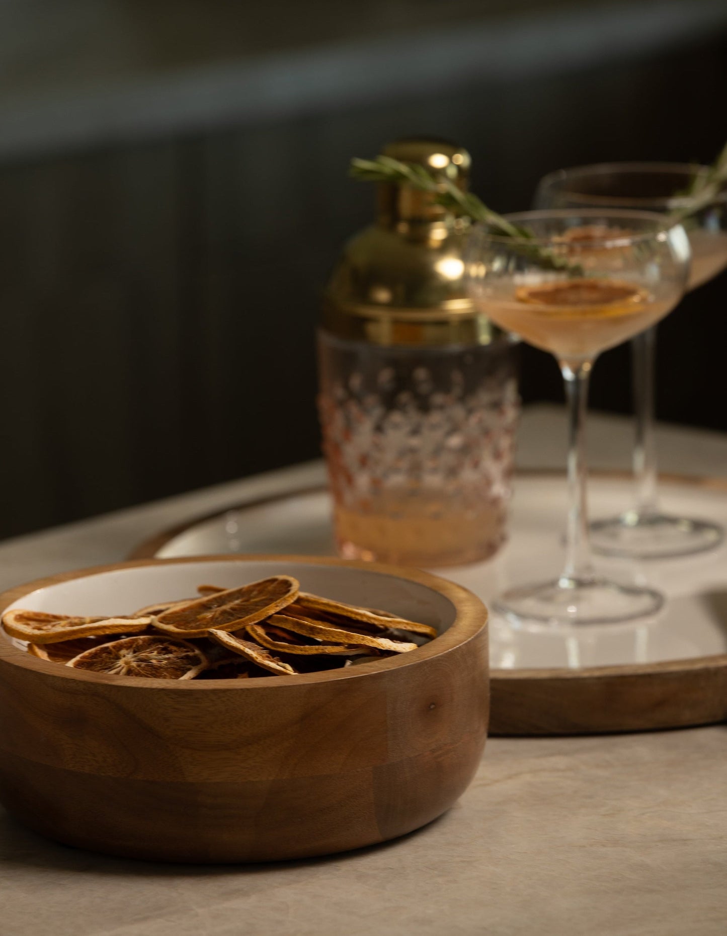 Wooden bowl with dried herbs on a table with a glass and bottle in the background