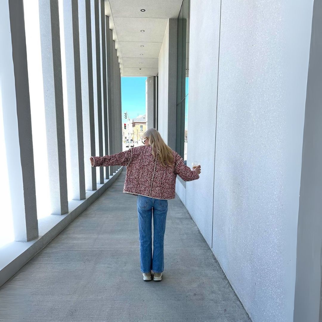 Person standing in a modern architectural hallway with open arms