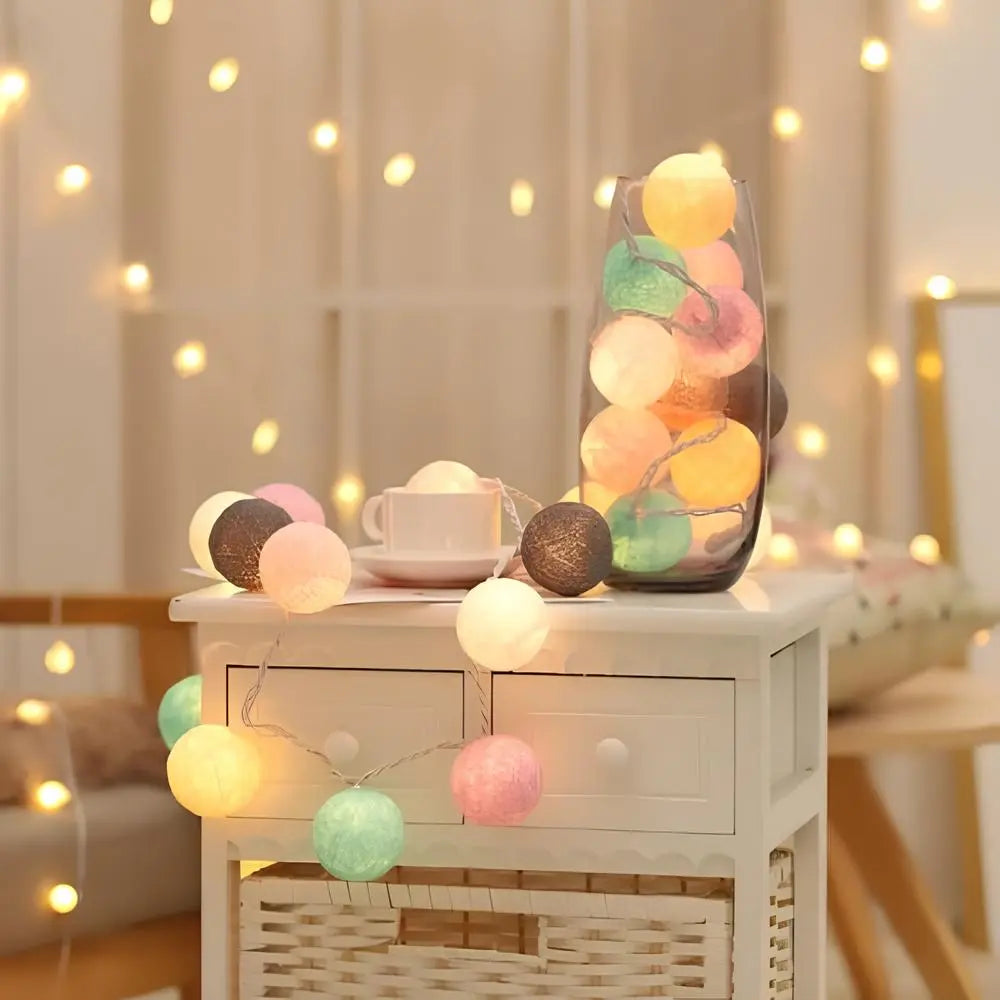 Decorative string lights with colorful balls on a small table in a softly lit room.