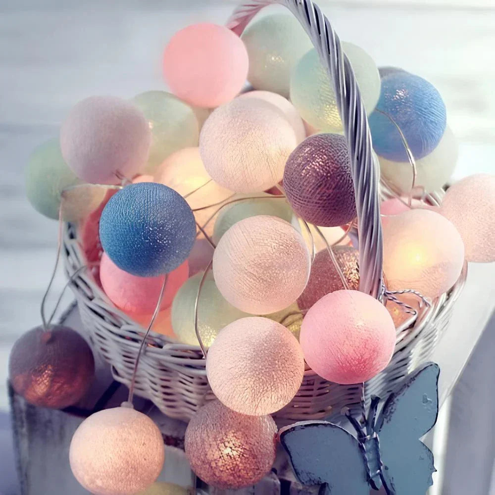 Colorful cotton ball string lights in a basket with a blurred background