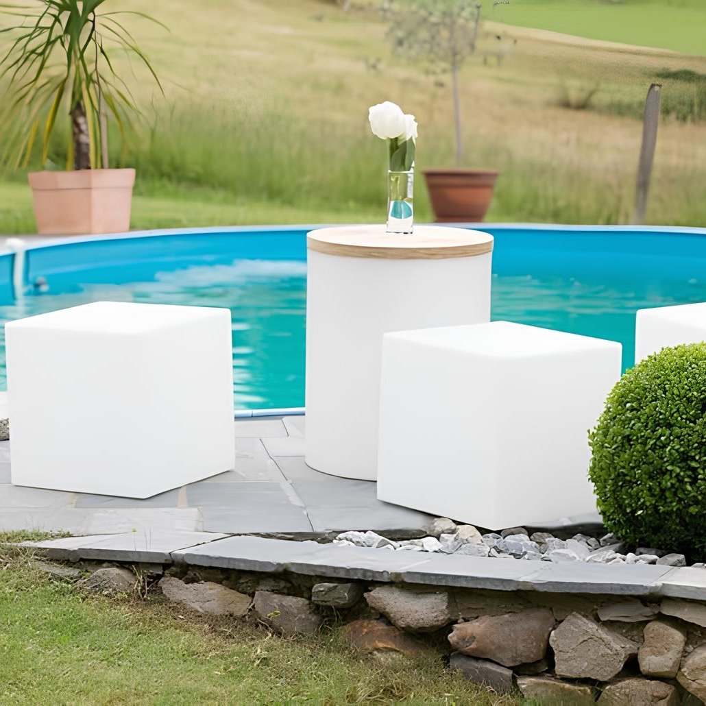 White outdoor furniture set by a pool with a vase of flowers on a table.