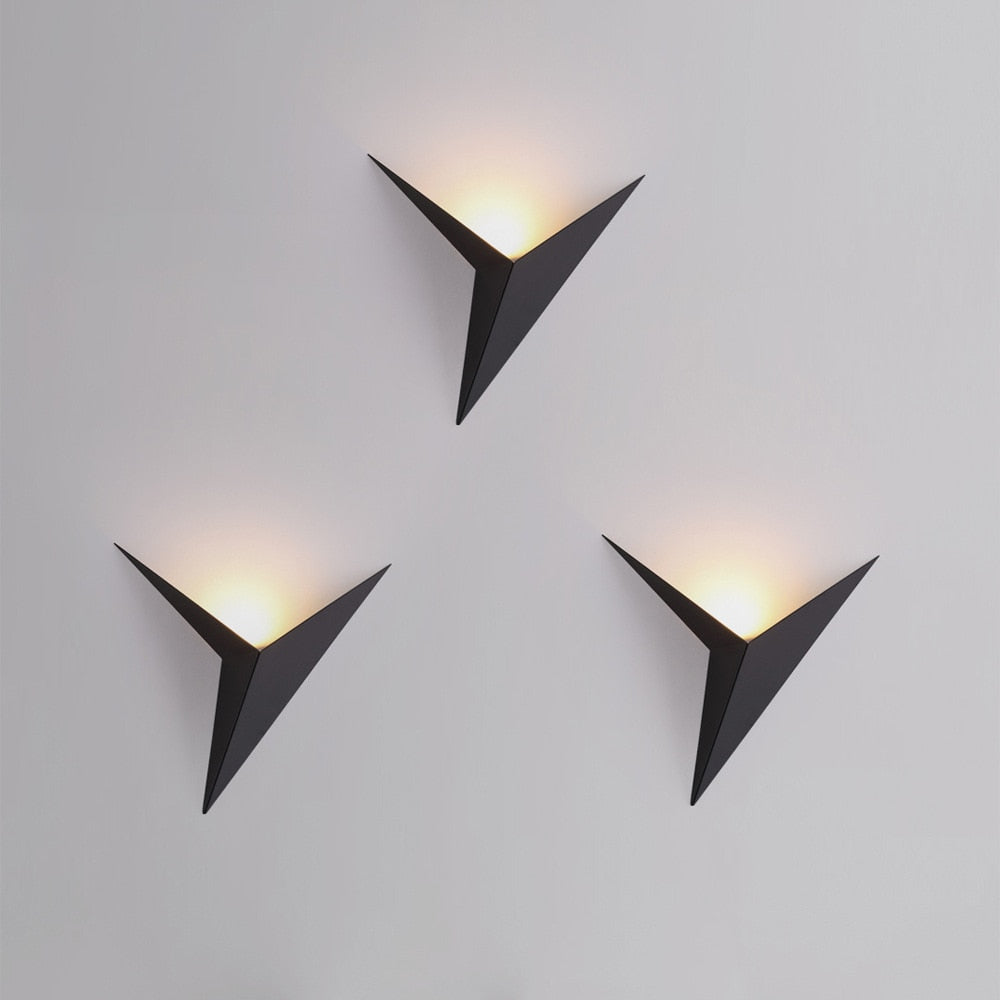 Three modern wall lights with triangular design on a gray background