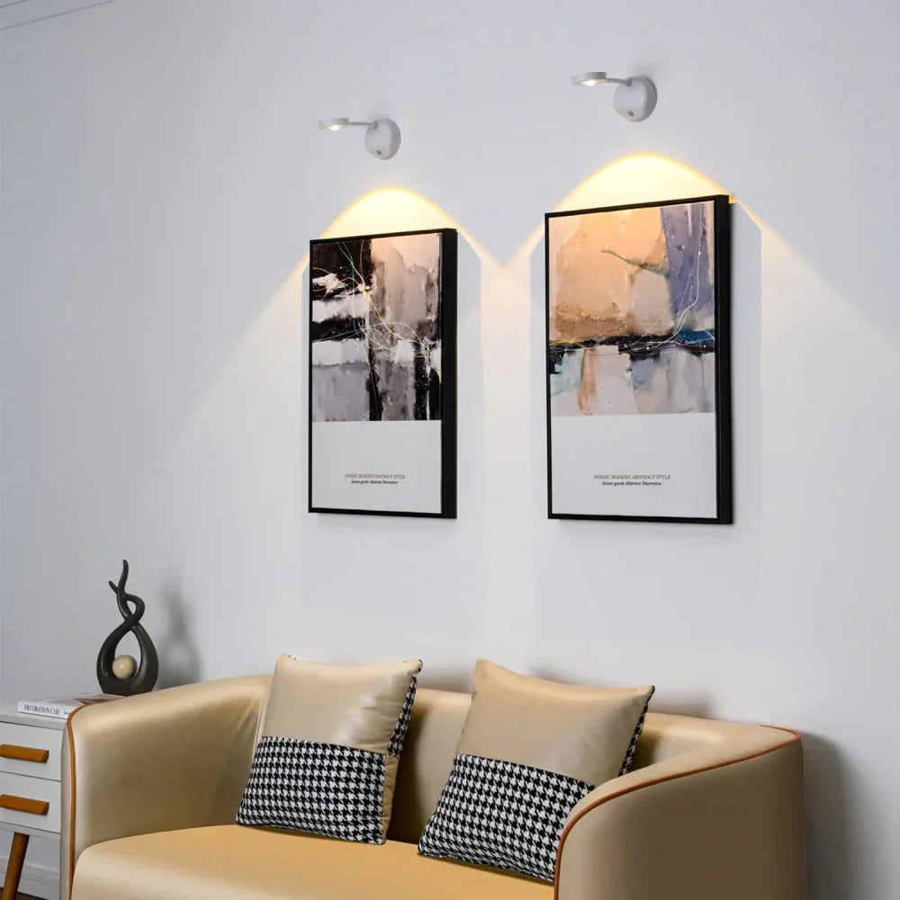 Beige sofa with decorative pillows in a room with abstract wall art and lighting fixtures.