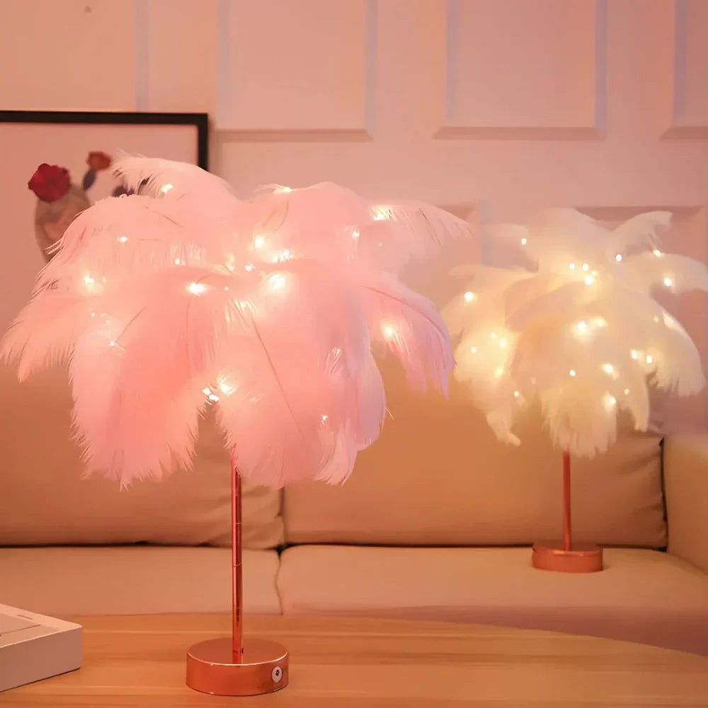 Pink feathered table lamp with string lights on a wooden surface, with a couch and decorative items in the background.