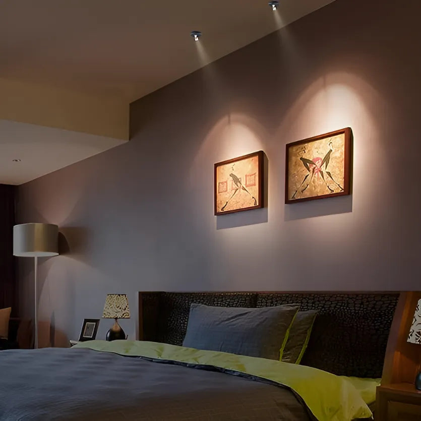 Bedroom with two framed artworks on the wall, a bed with green and blue bedding, and a lamp.