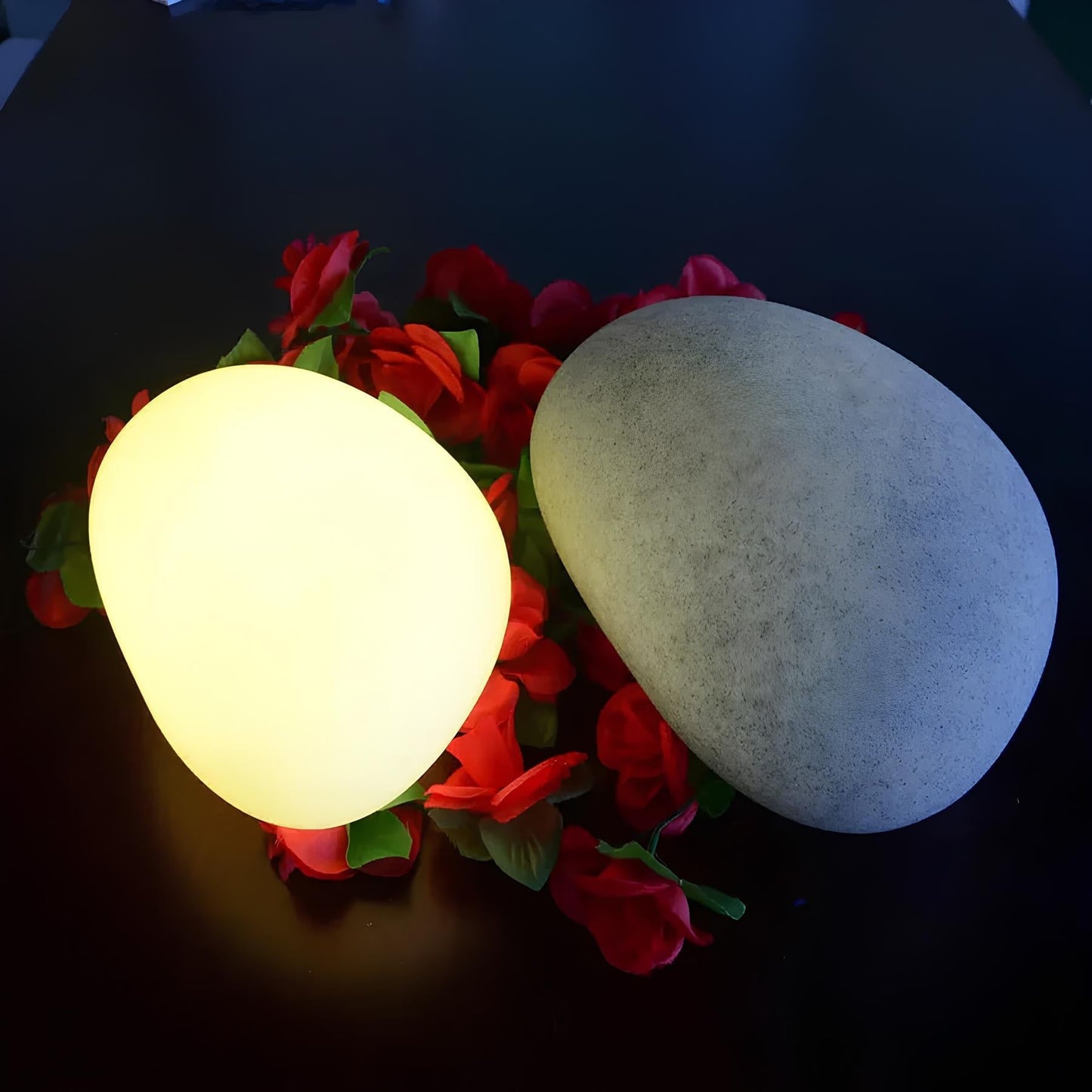 Glowing spherical light bulb on a bed of red flowers against a dark background