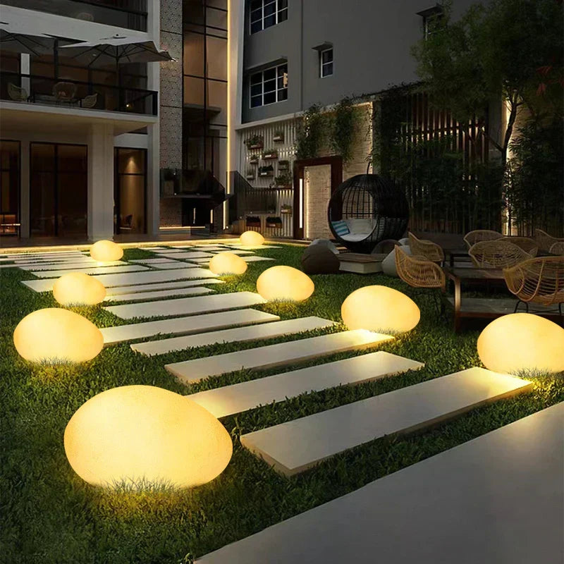 Outdoor patio area with illuminated spherical lights on grass