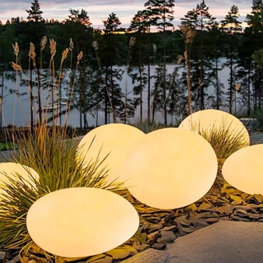 Glowing spherical outdoor lights on a natural setting with trees and water in the background