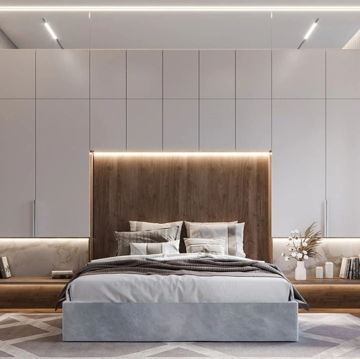 Modern bedroom with a bed, wooden headboard, and light gray walls.