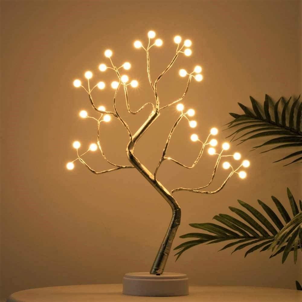 Decorative LED tree lamp on a neutral background with a plant.