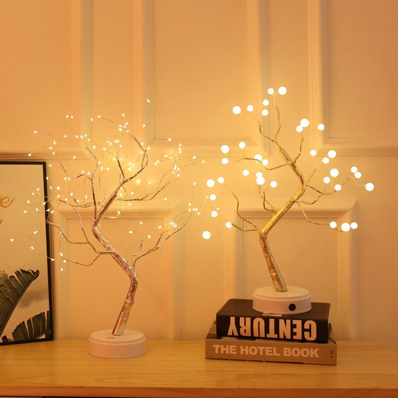 Decorative LED tree lights on a wooden surface with a book in the background