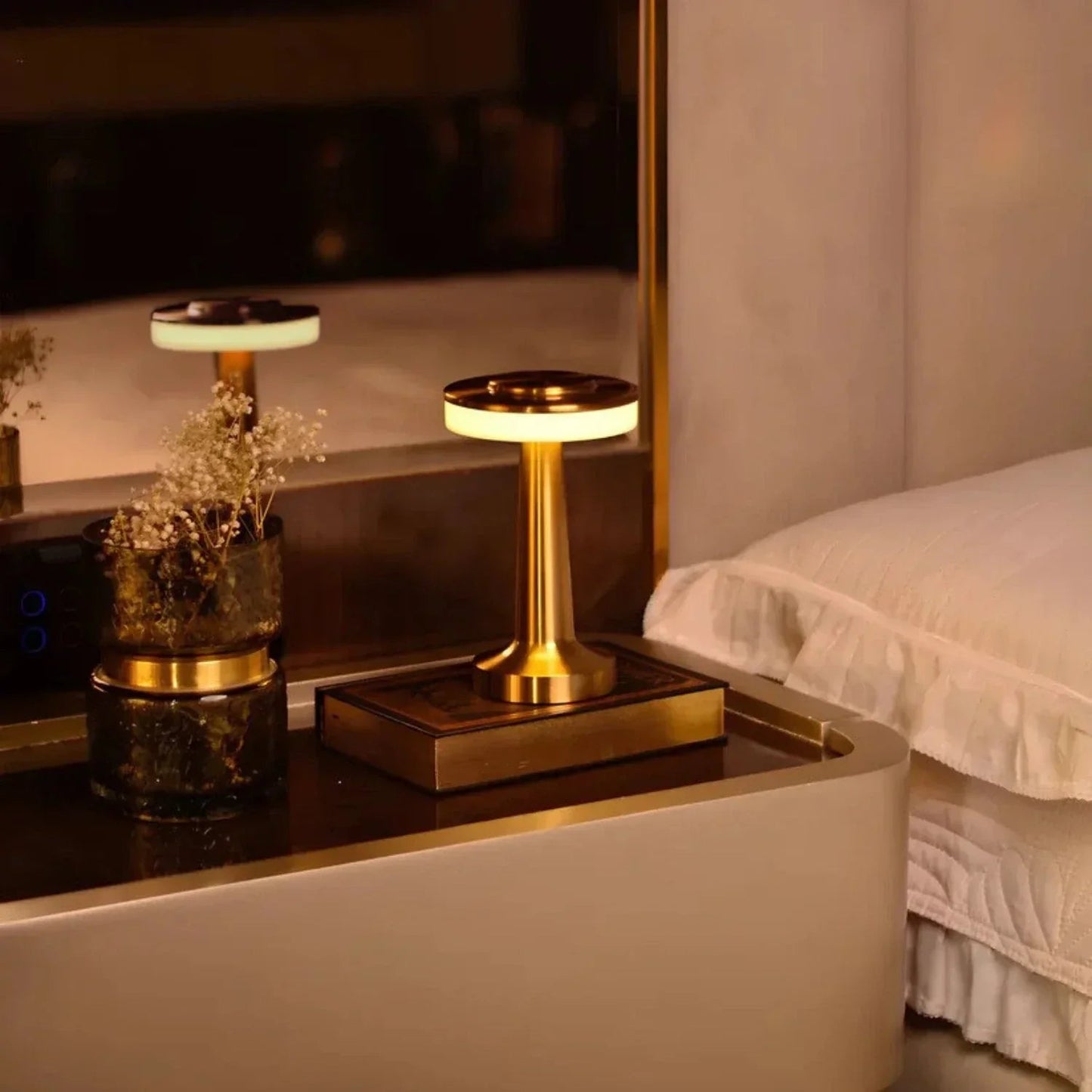 Gold nightstand with lamp and decorative items next to a bed
