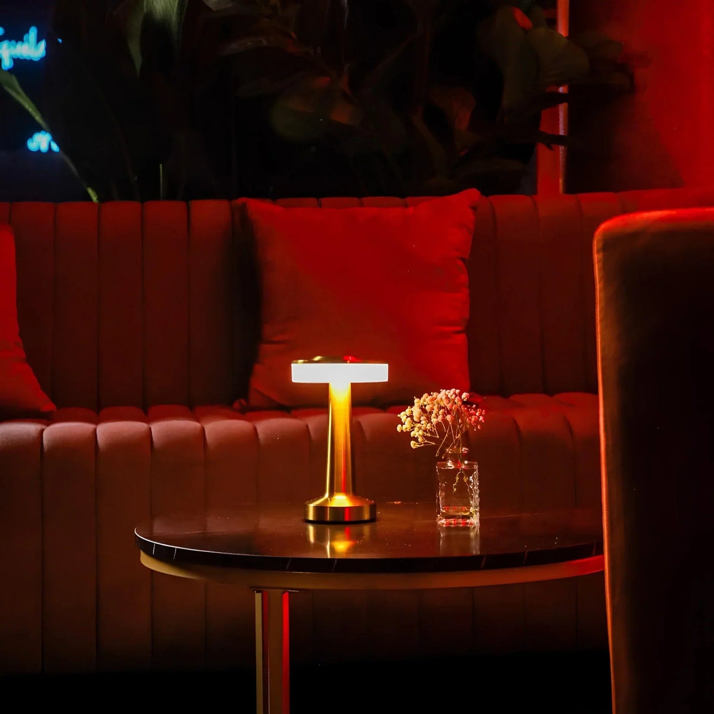 Red couch with a small table holding a lamp and a glass of water in a dimly lit room.