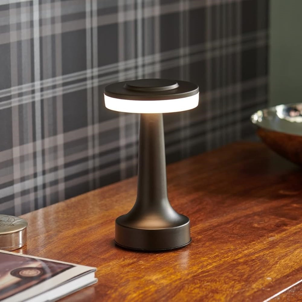 Modern lamp on a wooden surface with plaid curtain in the background