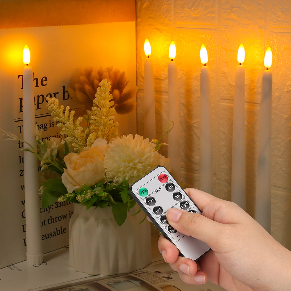Hand holding a remote control with LED candles and flowers in the background