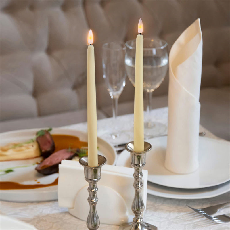 Elegant dinner setting with candles, plates, and cutlery on a table.