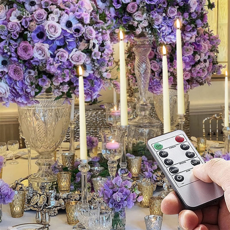 Decorative table setting with purple flowers, candles, and a remote control.